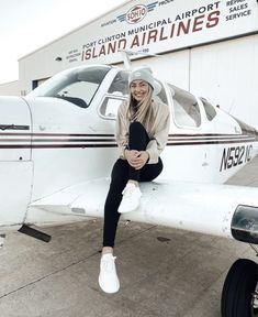 a woman sitting on the wing of an airplane