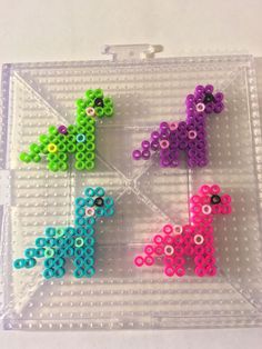 three different colored beads sitting on top of a plastic tray with holes in the shape of giraffes