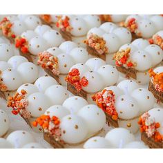 there are many white eggs with red and orange sprinkles on them in rows