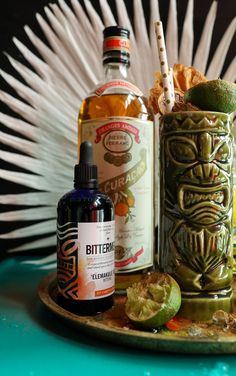 an assortment of alcohols and condiments sit on a tray with feathers in the background