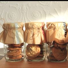 three glass jars with cookies in them sitting on a table