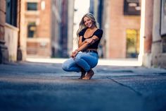 a woman kneeling down in the middle of an alley way with her hands on her knees