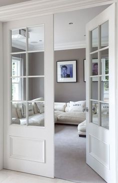 an open door leading to a living room with a white couch and large mirror on the wall