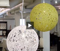 two white and yellow balls hanging from the ceiling in an office space with computers on the desks