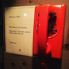 an old fashioned red phone is next to a sign