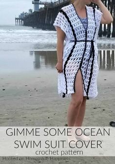 a woman standing on the beach wearing a white crochet cover with black trim