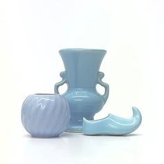 two blue vases sitting next to each other on a white surface with an apple in the foreground