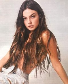 a woman with long brown hair and tattoos on her chest is posing for a photo