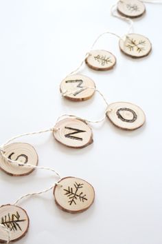 some wood slices with letters and snowflakes hanging from strings on a white surface