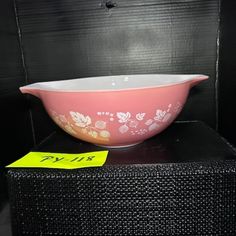 a pink bowl sitting on top of a black table next to a yellow sign that says,