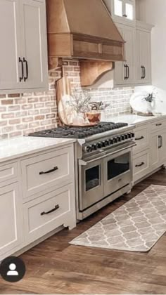 a kitchen with white cabinets and an oven in the center, along with a rug on the floor