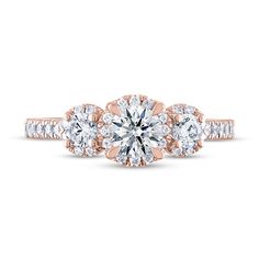 a rose gold engagement ring with three diamonds on the band and an oval center stone