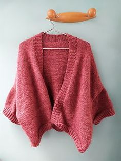 a pink sweater hanging on a hanger next to a pair of scissors and an object