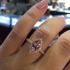 a woman's hand with a pink diamond ring on it