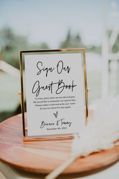 a close up of a table with a sign on it and a white feather laying next to it