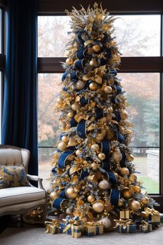 a decorated christmas tree with gold and blue ornaments in front of a large windowsill