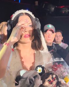 a woman in a wedding dress holding her hands to her face with other people behind her