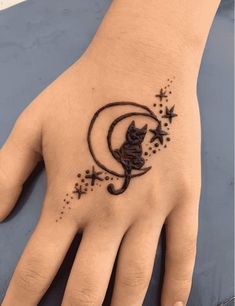 a hand with a cat on it and stars in the sky around it, as well as a crescent moon tattoo