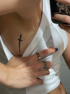 a woman with a cross tattoo on her chest holding a cell phone and looking at the camera