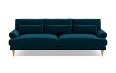 a blue couch with wooden legs and pillows on the back, sitting in front of a white background