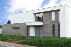 a white and grey brick building sitting on the side of a road next to a lush green field