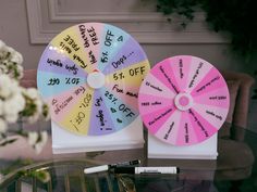 two wheel of fortunes sitting on top of a table next to a vase with flowers