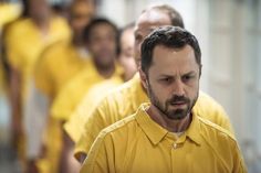 a group of men in yellow shirts walking down a hallway together with one man looking at the camera