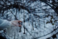 a person holding an umbrella with many keys hanging from it's sides in front of a tree