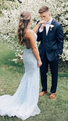 the bride and groom are standing in front of some white flowers, one is holding his hand up to his mouth