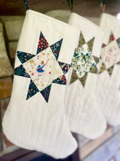 quilted christmas stockings hanging from hooks in a store window with star designs on them