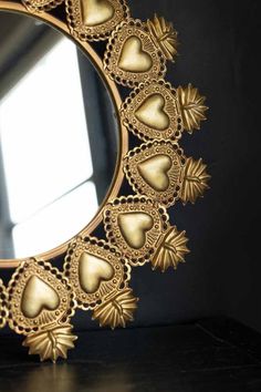 a mirror that is on top of a table next to a black wall with gold hearts