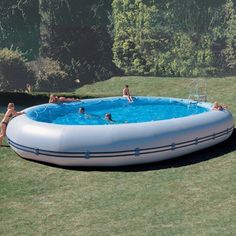 an inflatable swimming pool with people playing around it on the lawn next to a house