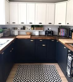 a kitchen with black and white flooring and wooden counter tops, along with an area rug on the floor