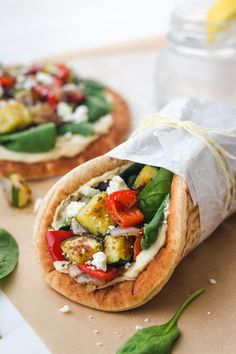 two pita breads with vegetables and other toppings sitting on a cutting board