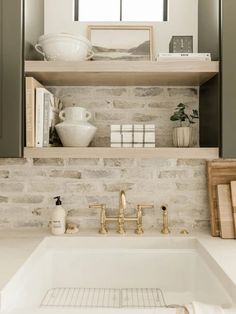 a white sink sitting under a window next to a shelf filled with books and other items