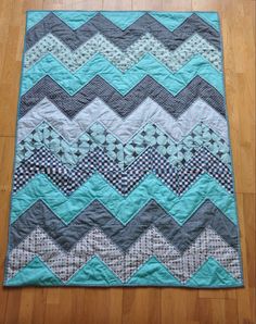 a blue and gray chevroned quilt sitting on top of a hard wood floor