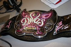 the belt is decorated with pink and white designs on it's side, along with other accessories