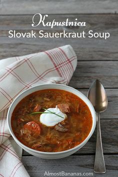 a white bowl filled with soup on top of a wooden table next to a spoon