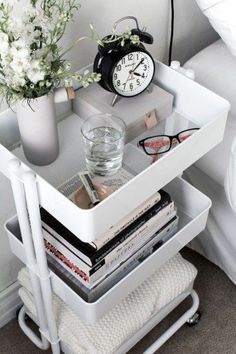 a white bedside table with magazines and an alarm clock