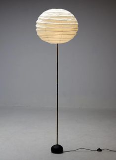 a floor lamp with a white paper ball on it's top and black base