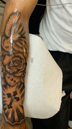 a man with a cross and roses tattoo on his arm