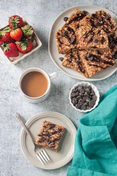 two plates with oatmeal and chocolate chip bars on them next to cups of coffee