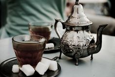 a tea pot and two cups filled with marshmallows