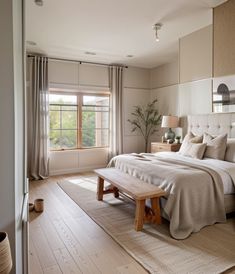 a bedroom with a large bed sitting next to a wooden bench in front of a window