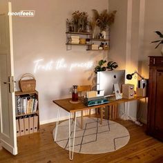 a desk with a computer on top of it next to a book shelf and plant