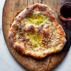 a pizza sitting on top of a wooden cutting board next to a glass of wine