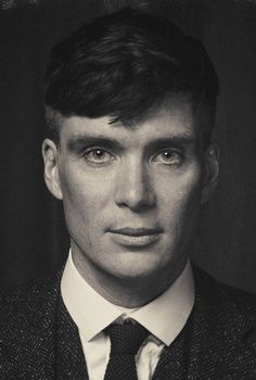 a black and white photo of a young man in a suit with a tie on