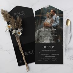 an elegant black and white wedding card with a photo on it, next to a dried flower