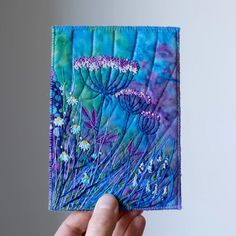 a hand holding up a piece of art with flowers painted on the inside of it