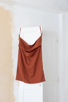 a brown top hanging on the wall in front of a white door with peeling paint